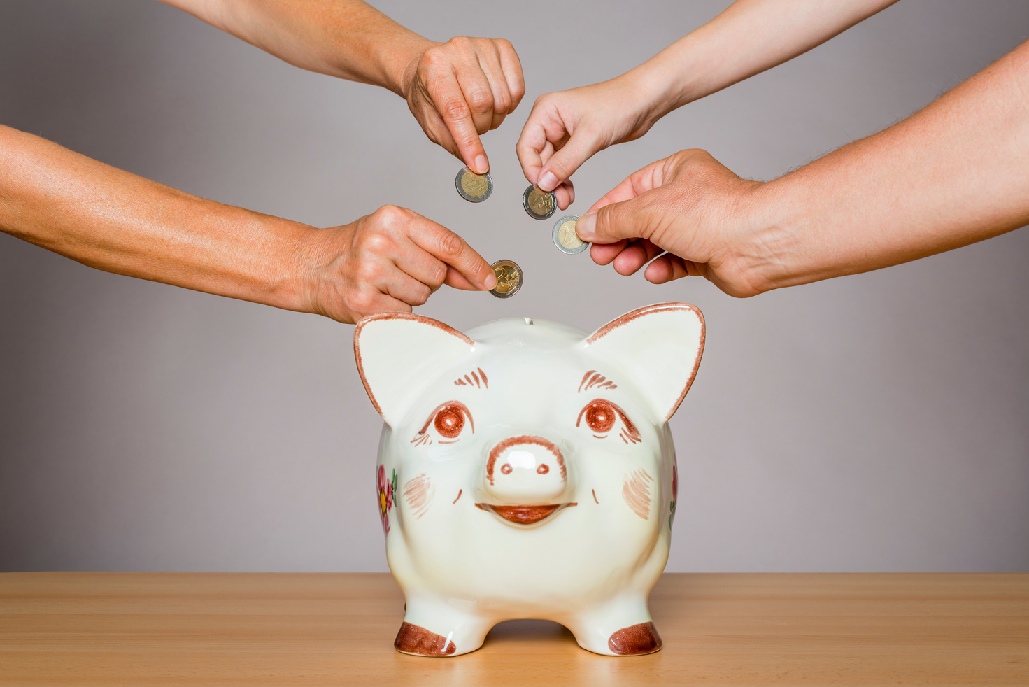 crowdfunding - people inserting money into piggybank